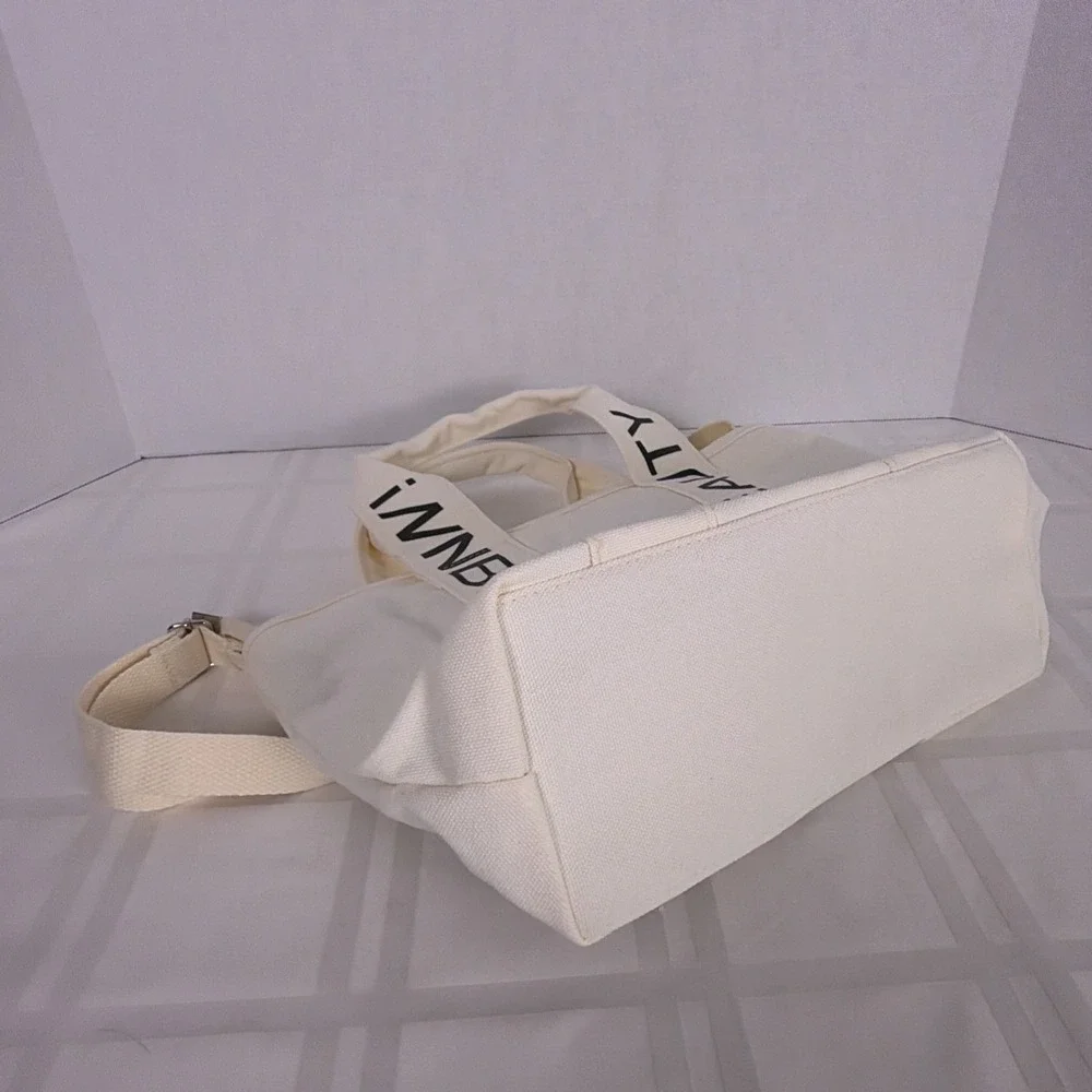 iNN BEAUTY bag off white tote bag with black letter branded straps.